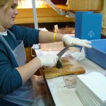 Person cutting fish head on cutting board with large knife